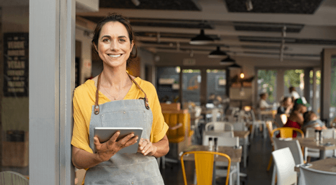 Unternehmerin mit Tablet vor ihrem Café