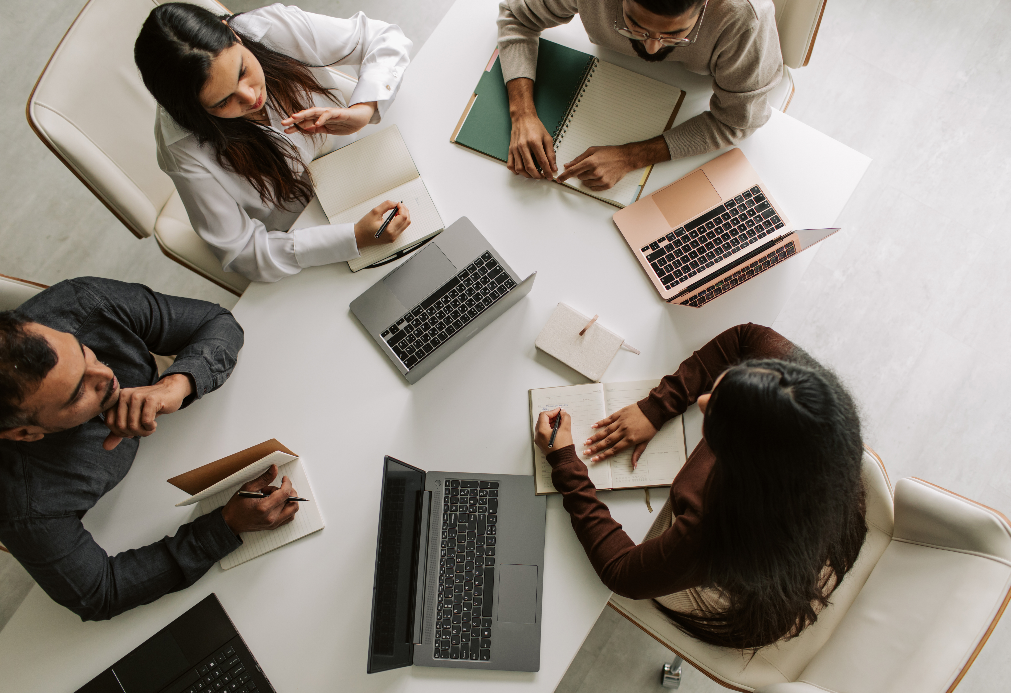 Marketing-Team arbeitet gemeinsam an einem Tisch mit Laptops und Notizen, von oben gesehen